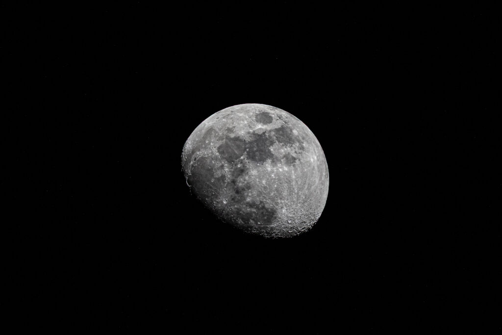 A detailed photograph of the moon against a pitch-black night sky, showcasing its craters and surface textures